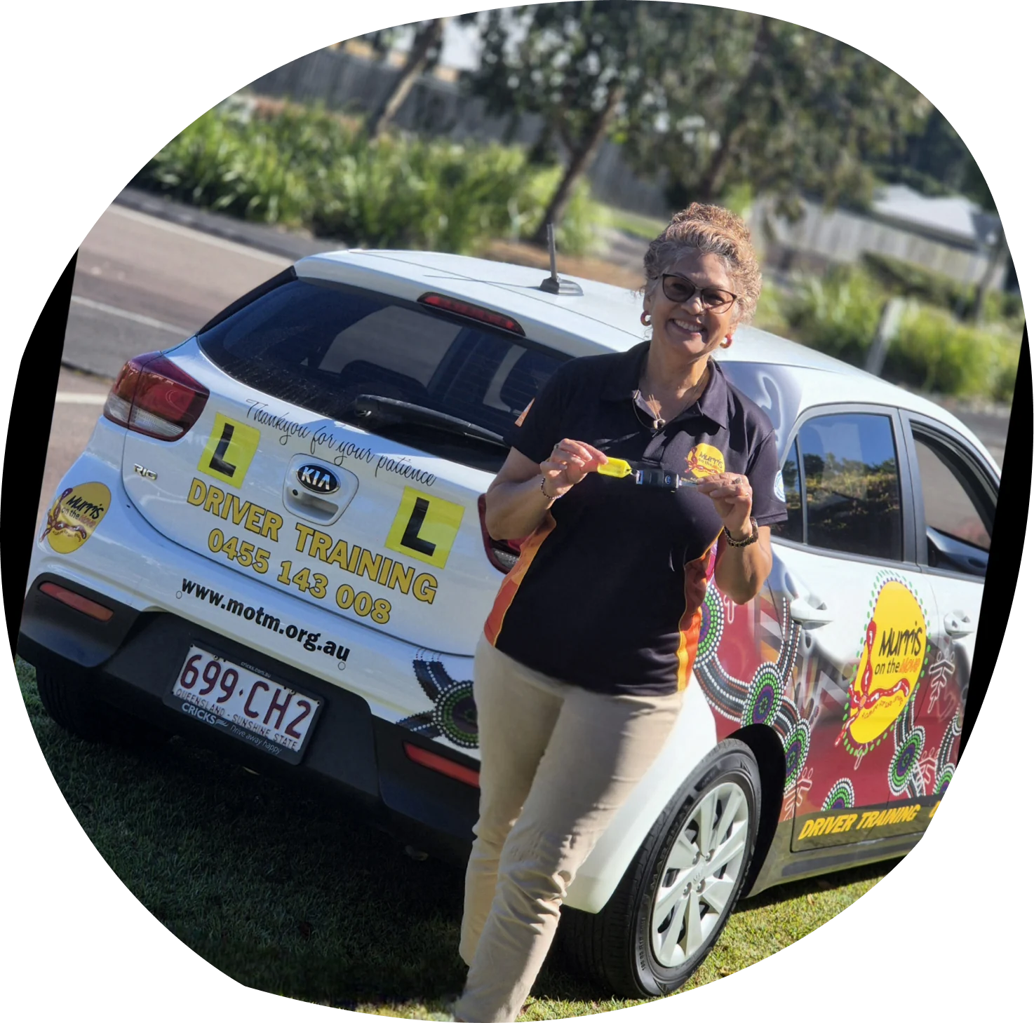 Kerri Turner standing in front of a Murri’s on the Move driver training car, holding up a set of keys.