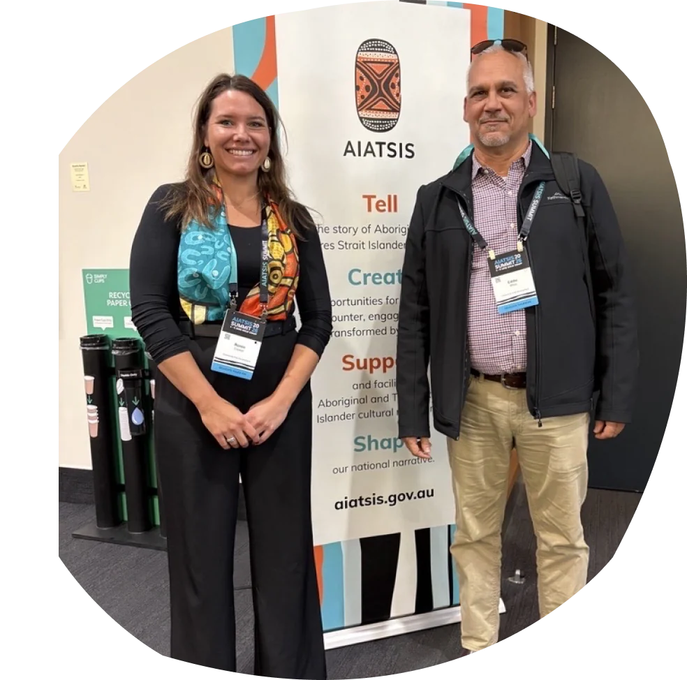 Two presenters smiling in front of an AIATSIS Summit banner.